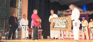 Michael Franki (Mitte) wird von seinen Schwarzgurten mit einem Bild beschenkt, auch der Präsident der International Okinawa Budo Federation und Großmeister Heinz Köhnen (links) freut sich.   Foto: Jehle