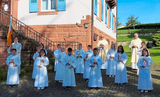 14 Kinder aus Seelbach und Wittelbach haben bei ihrer Erstkommunion ihre Taufkerzen erhalten. Im Hintergrund sind Pfarrer Johannes Mette (links) und Diakon Klaus Heuberger.  Foto: Vögele