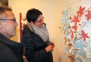 Eine Besucherin betrachtet ein Werk von Regine Staudenmeyer-Türk. Sie hat aus Tapeten Blumen und Blüten ausgeschnitten und  verarbeitet.  Foto: Haberer Foto: Lahrer Zeitung