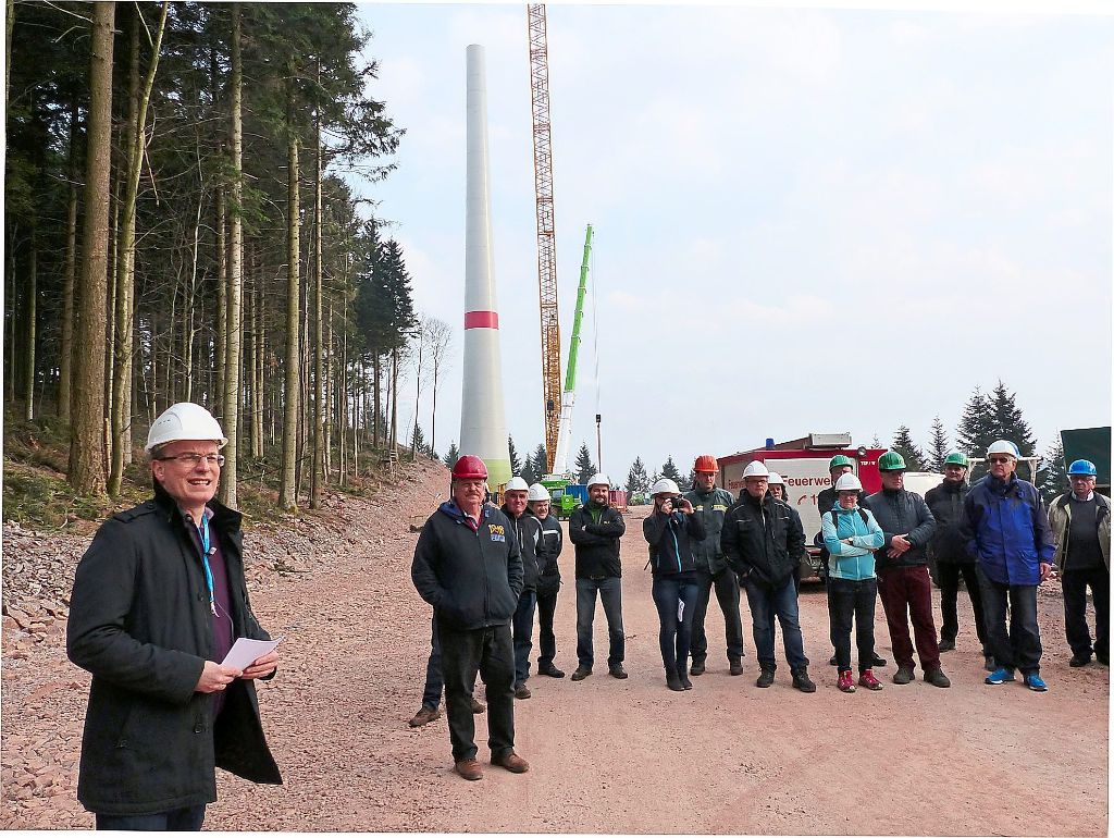 Der Gegenbacher Bürgermeister Thorsten Erny (links) begrüßt die Teilnehmer an der Begehung der Baustelle. Die Rotorspitzen des Windrads im Hintergrund sollen bei Inbetriebnahme bis in eine Höhe von fast 150 Metern erreichen.  Foto: Vögele
