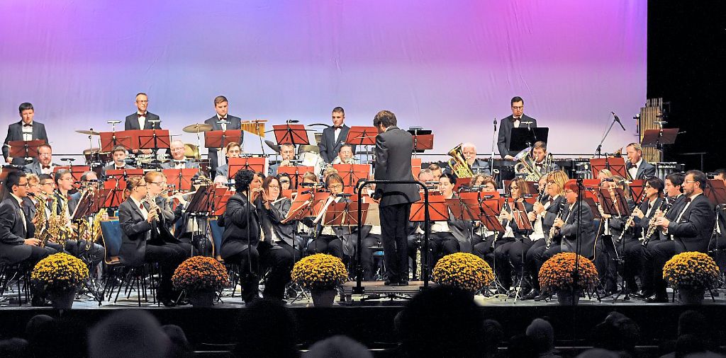 Die Stadtkapelle mit Dirigent Nicholas Reed auf der Stadthallenbühne, die passend zum Konzertanlass mit Chrysanthemen geschmückt war.