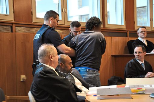 Das Foto der Verhandlung zeigt, wie der Angeklagte zu seinem Platz geführt wird. Rechts hinten ist Staatsanwalt Kai Stoffregen zu sehen, davor Strafverteidiger Marc Kutschera. Links sitzt Verteidiger Achim Lederle, danaben der Dolmetscher. Foto: Schabel