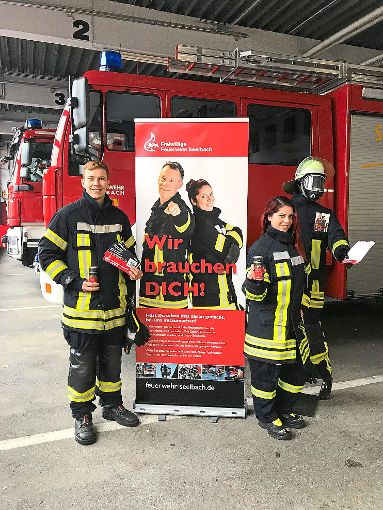 Die Feuerwehr-Einsatzkräfte Rico Dach und Christine Vetter posieren mit Broschüren und Getränkedosen vor dem großen Werbebanner. Ihre Gesichter finden sich auch auf den Werbeplakaten wieder.  Foto: Feuerwehr